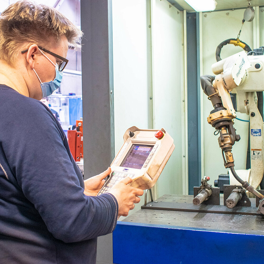 Frau mit Maske arbeitet an Maschine